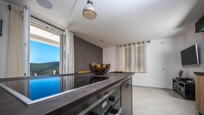 A modern kitchen with a large island, a built-in oven, and a view of the outdoors. - Beautiful 1-bed Apartment in Pobrezje-dubrovnik (Dubrovnik)