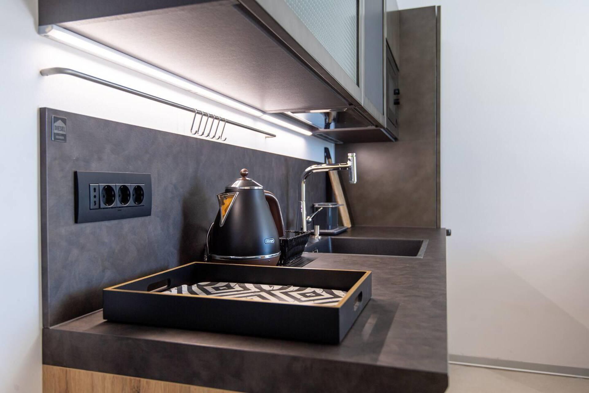 Une cuisine moderne équipée d’une machine à café intégrée, d’un plateau orné d’un motif géométrique et d’une prise de courant.