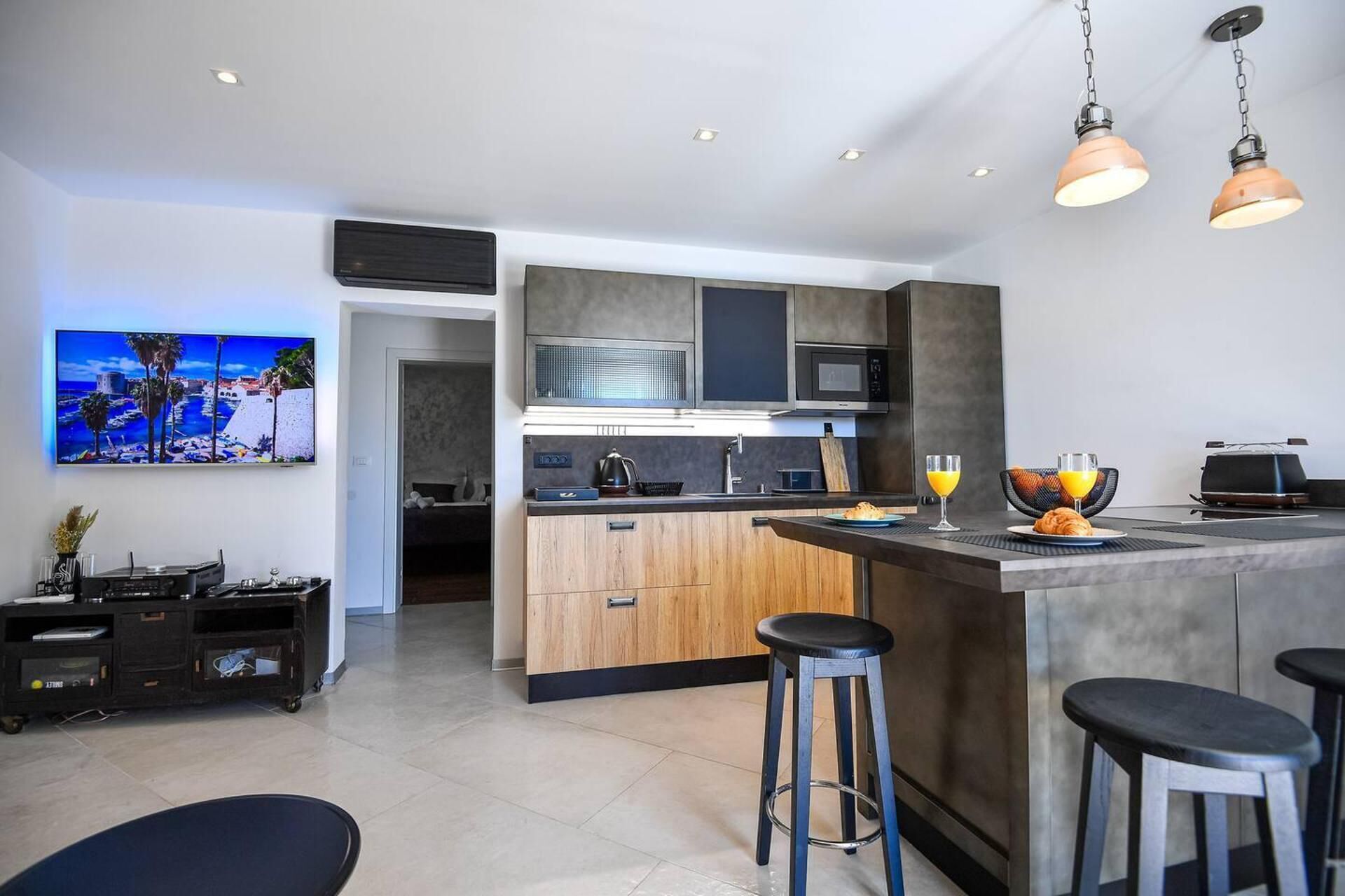 A modern kitchen with a central island, bar stools, and a dining area.