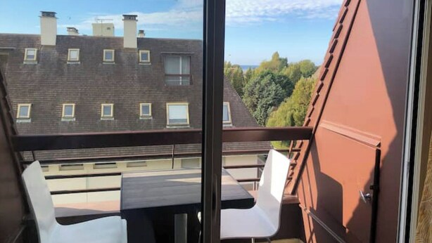 Een balkon met een tafel en stoelen, met uitzicht op een woongebied met meerdere gebouwen en bomen.