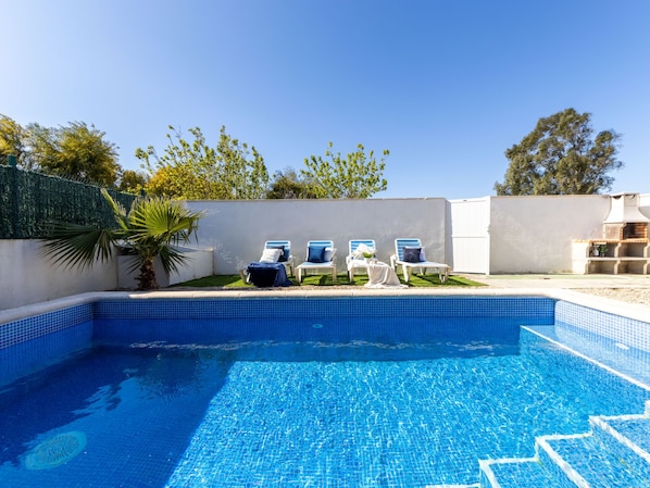 A swimming pool with blue tiles, surrounded by white walls and a palm tree. - Tropical 2 by Interhome (Deltebre)