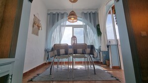 Un comedor con una mesa y sillas, una lámpara colgante y vistas a través de una ventana.
