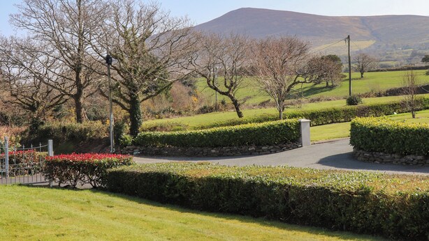 A landscaped garden with manicured hedges, a paved path, and a variety of trees. - Gap of Dunloe (Killarney)