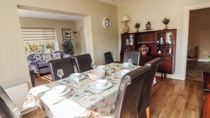 A dining area with a table set for four, surrounded by chairs. There is a clock on the wall and a cabinet with glassware. - Gap of Dunloe (Killarney)