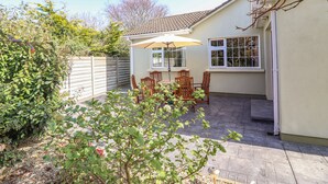 A patio with a table and chairs, a small garden, and a white building with windows. - Gap of Dunloe (Killarney)