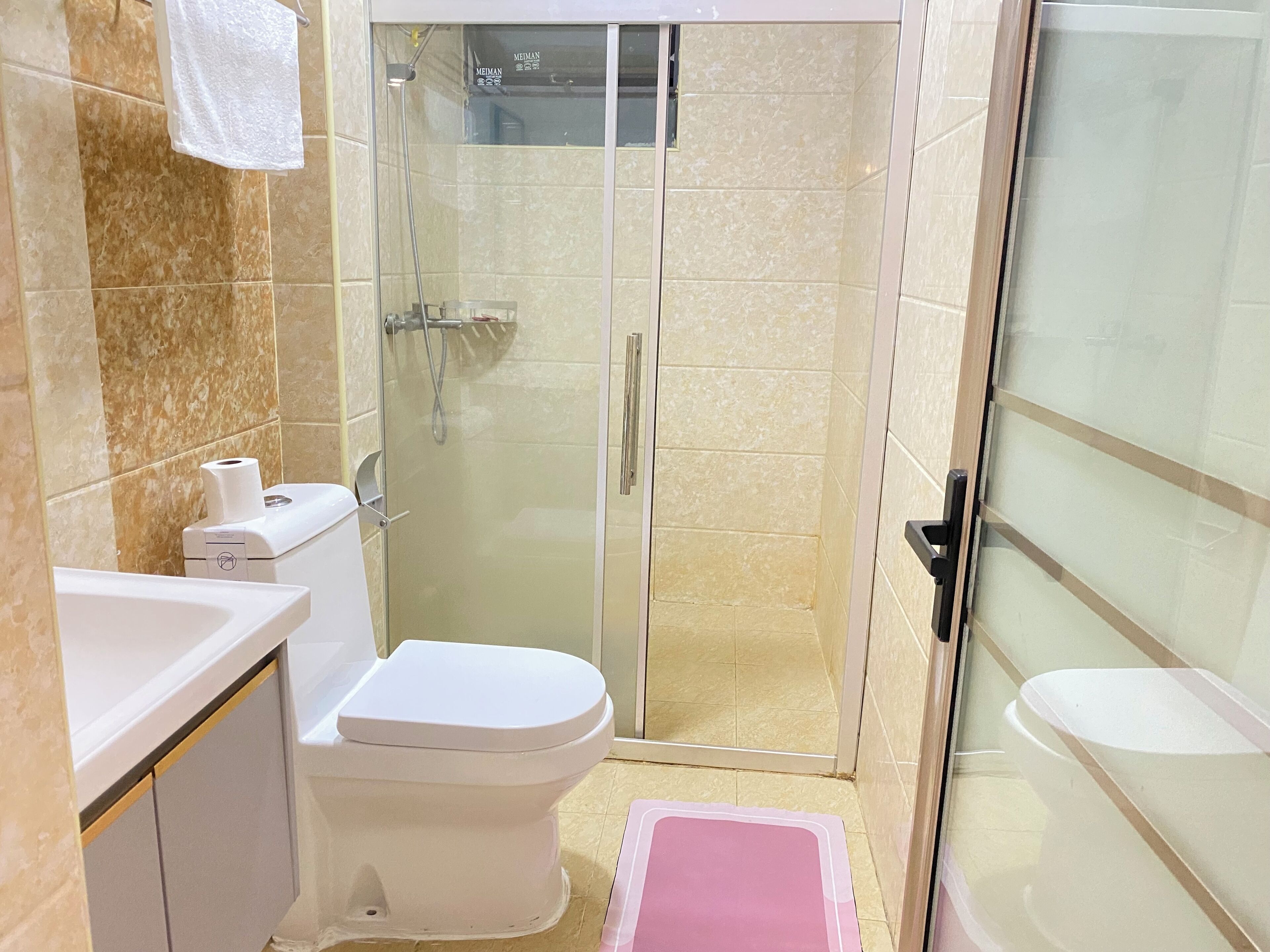 A bathroom with a toilet, a shower with a glass door, and a sink.
