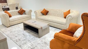 Una sala de estar moderna con dos sofás color crema, una mesa de centro de madera y un sillón a juego.