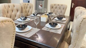 Una mesa de comedor dispuesta para cuatro personas con sillas a juego, un refrigerador y una puerta al fondo.