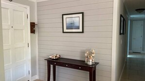 A hallway with a wooden console table, a framed picture on the wall, and a door.