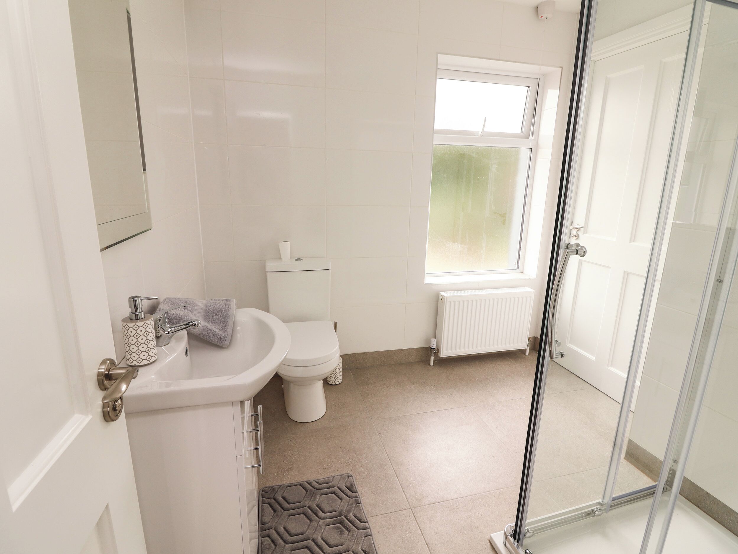 A bathroom with a toilet, sink, and a window.