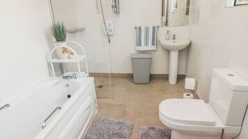 Une salle de bain moderne équipée d’une baignoire, de toilettes, d’un lavabo et d’une douche.