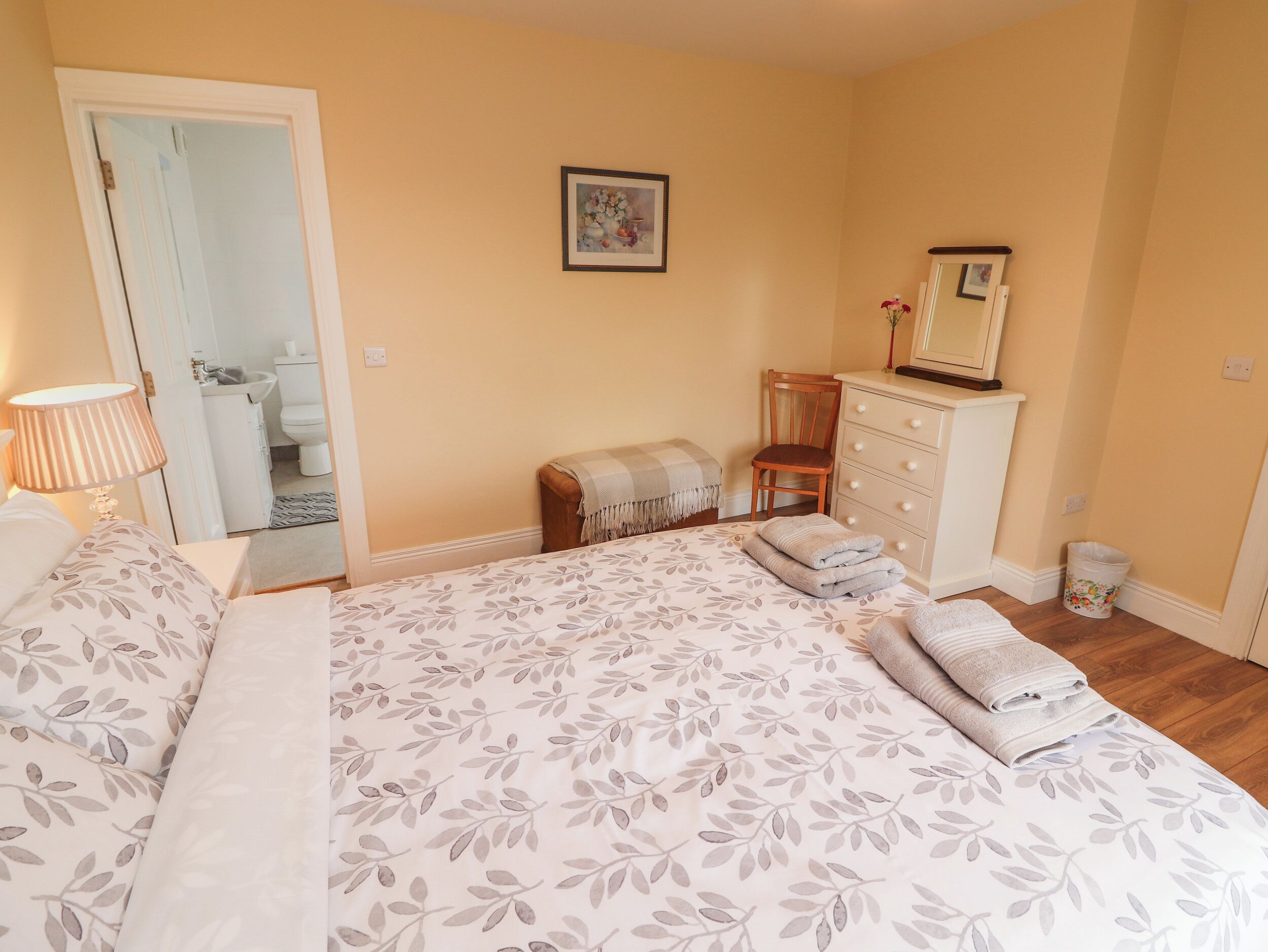 A bedroom with a bed, a chair, a dresser, and a mirror.