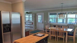 Una cocina con refrigerador de acero inoxidable, encimera de madera y un comedor con mesa y sillas.