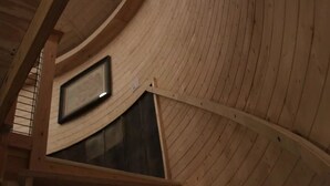 Een houten interieur met een gebogen plafond en een groot raam.