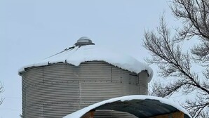 Een cilindervormige metalen constructie met een sneeuwbedekte dak en een klein terras.