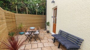 A patio with a wooden table and chairs, a bench, and potted plants.
