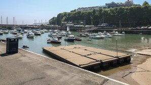 A marina with boats docked, a concrete platform, and a building in the background.