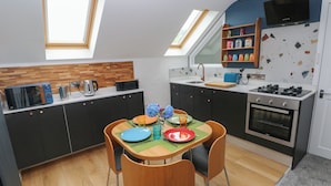 A compact kitchen with a dining area, featuring a microwave, kettle, and a stove.