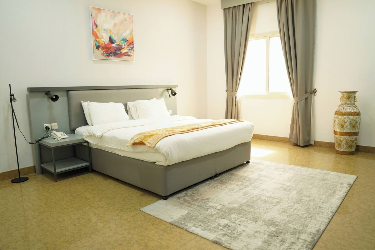 A neatly arranged bedroom with a bed, bedside table, and a vase.