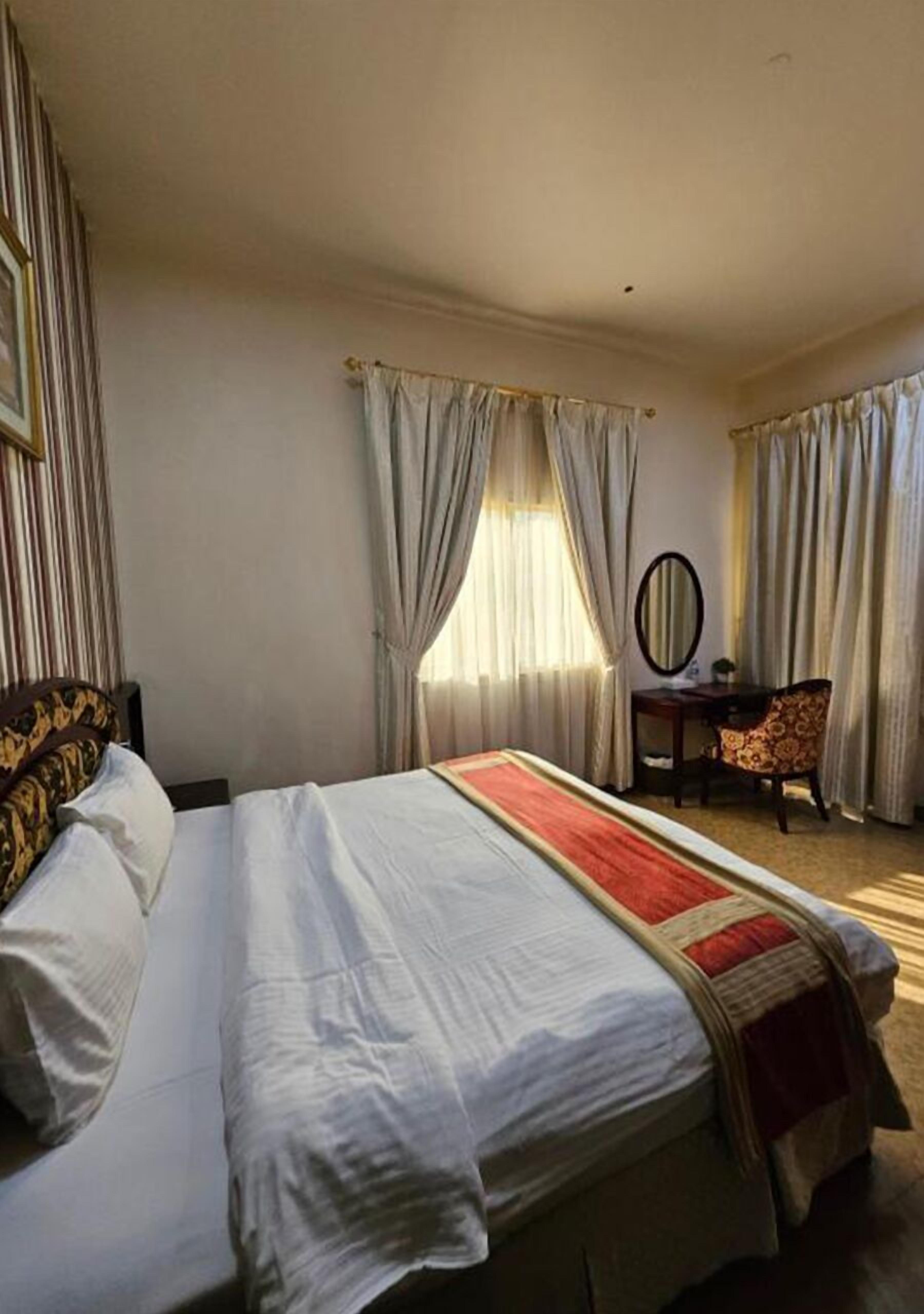 A hotel room with a large bed, a desk, and a chair.
