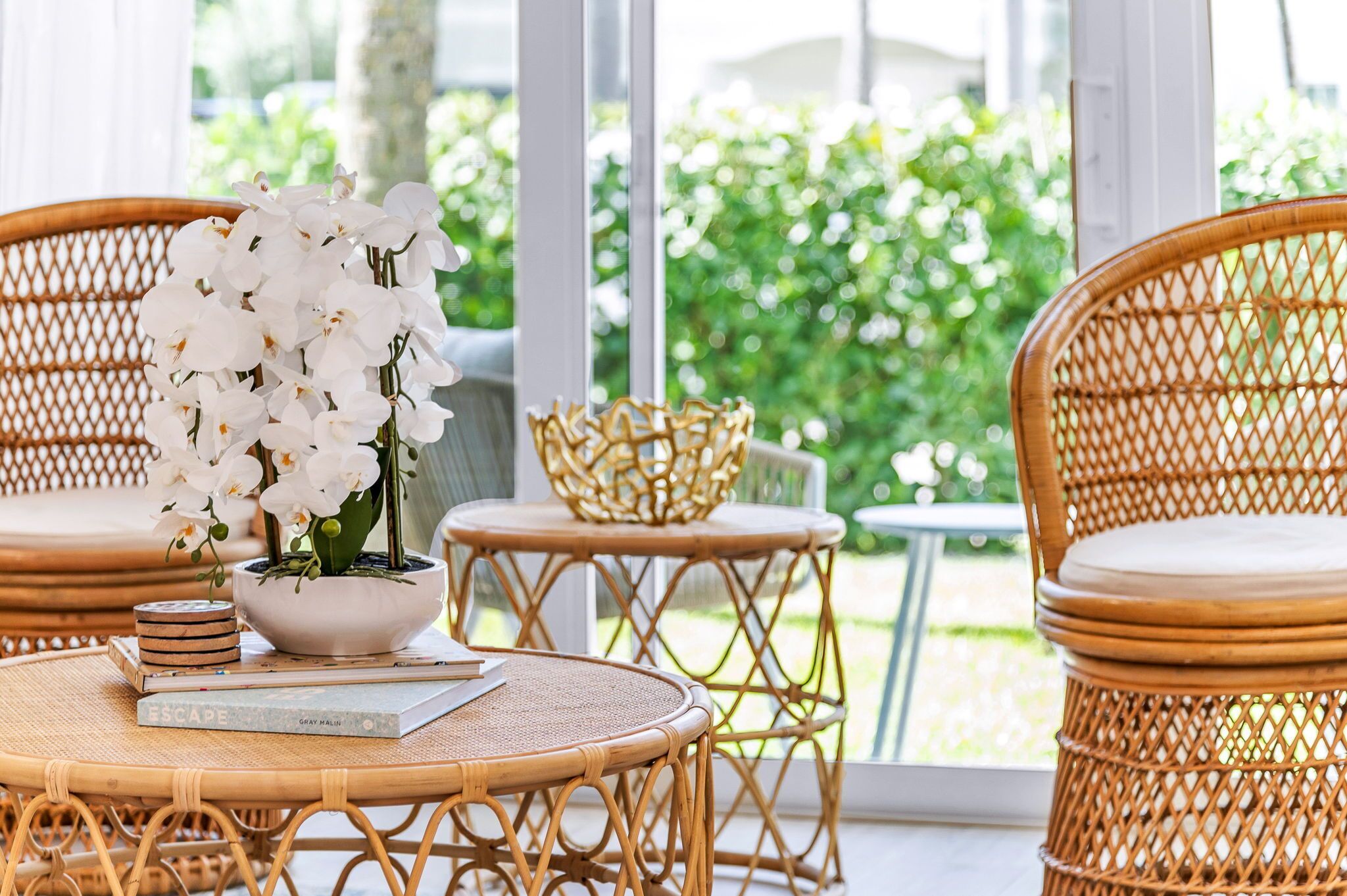 A wicker dining set with a potted orchid and a book on a table.