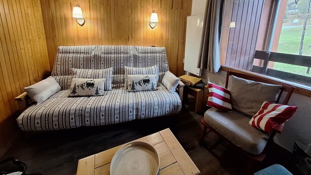 A cozy room with a striped sofa, a wooden table, and a window with curtains.