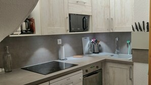 A compact kitchen with white cabinets, a microwave, a dishwasher, and a sink.