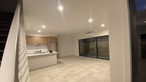 A modern kitchen with a central island, a dining area, and a sliding glass door leading to a balcony. - Unfurnished-2 Story 3 Bedroom House- 30min to Melbourne international Airport (South Morang)