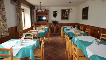 Un comedor con varias mesas y sillas, un televisor y una estantería.