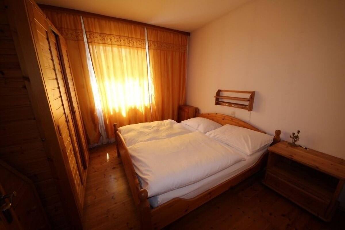 A wooden bed with white bedding in a room with wooden walls and floors.