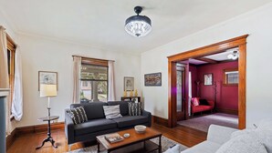A living room with a black sofa, a grey sofa, a wooden coffee table, and a chandelier.