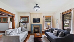 A living room with two sofas, a fireplace, a television, and a chandelier.