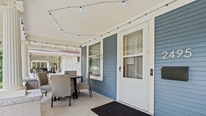 A covered porch with a dining table and chairs, a mailbox, and a house number 2495.