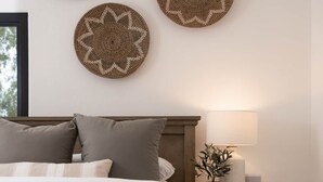 Un dormitorio con una cama de madera, una mesita de noche con una lámpara y tres placas decorativas colgadas en la pared.