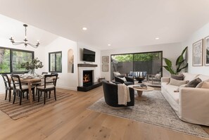 A modern living room with a fireplace, a dining area, and a sofa. - Villa Muralla | Stylish 2BR Near State Street & SB Bowl (Santa Barbara)