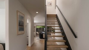 Una escalera moderna con peldaños de madera y barandillas negras, que conduce a un espacio de estar con un sofá y una mesa de centro.