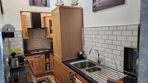 A compact kitchen with wooden cabinets, a black countertop, and a stainless steel sink.