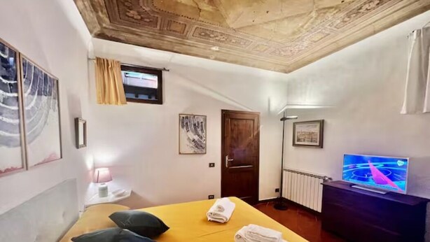 Ein Hotelzimmer mit Bett, Fernseher, Tür und einem Vorhangfenster.