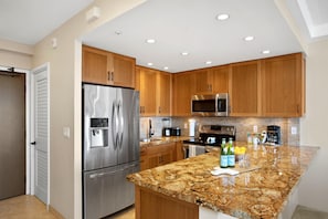 A modern kitchen with stainless steel appliances, wooden cabinets, and a granite countertop.