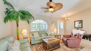 Ein Wohnzimmer mit einem grünen Sofa, einem braunen Ledersessel, einer Holzbank und einem Deckenventilator.