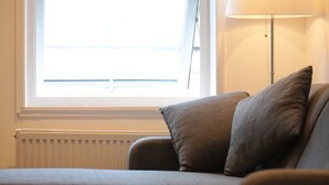 Ein Wohnzimmer mit einer Couch, einer Lampe, einem kleinen Tisch und einer Heizung.