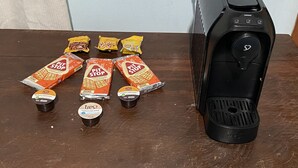 Una moka, diverse cialde di caffè e qualche bustina su un tavolo di legno.