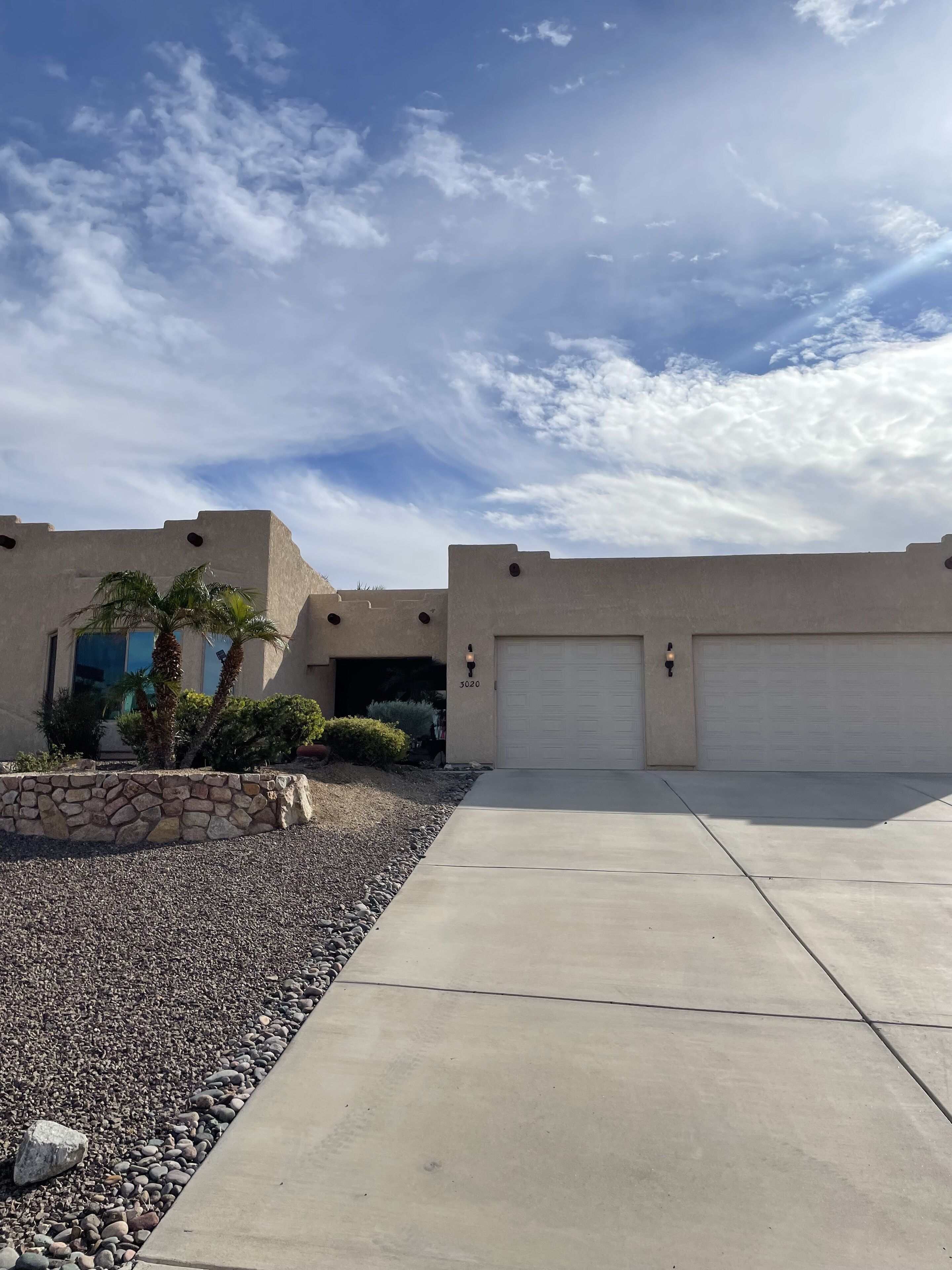A residential area with a paved driveway, a stone wall, and a garage door.