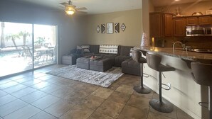 A spacious living area with a large sectional sofa, a dining table, and a kitchen with modern appliances. - Sante Fe Style pool home (Lake Havasu City)