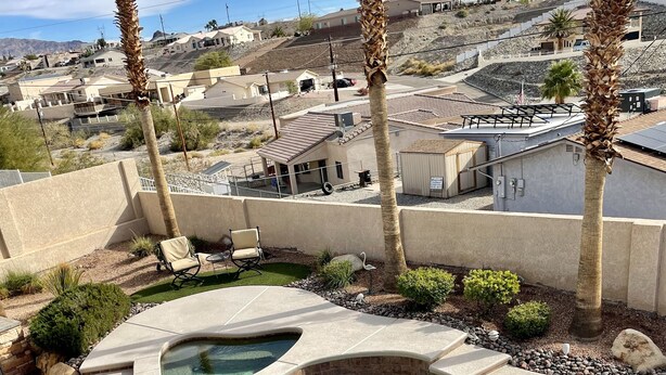 A swimming pool with a curved design, surrounded by palm trees and a patio area with chairs. - Sante Fe Style pool home (Lake Havasu City)