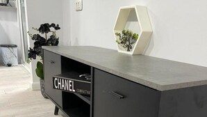Un mueble moderno de color gris oscuro en forma de L, con un cartel que dice 'CHANEL COMPACT NAT' en el frontal del cajón.