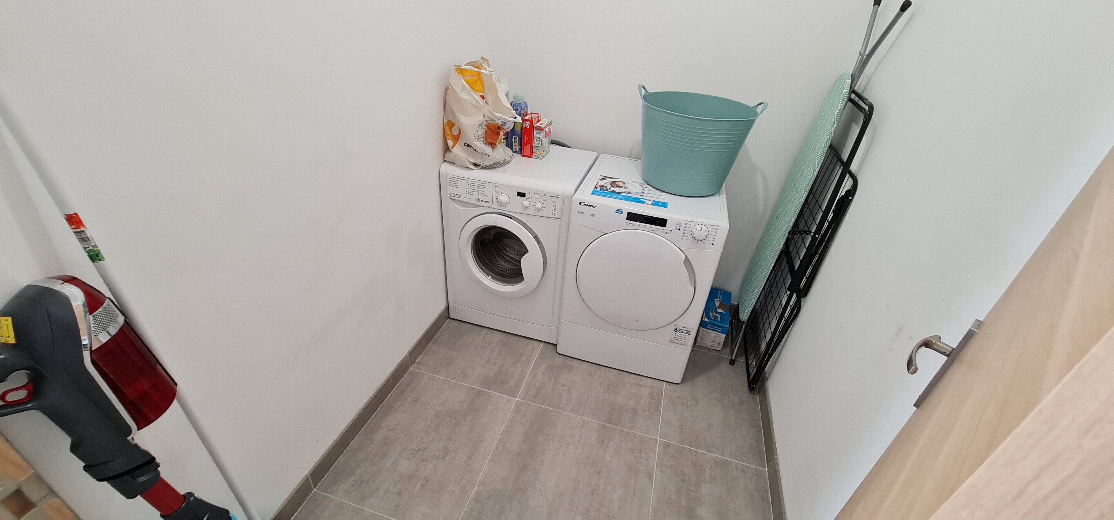 A laundry area with a washing machine and dryer, a bucket, and a mop.