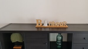 Tumma puinen lipasto, jossa on hylly, ja hyllyllä on esillä sana »Bancheur» sekä Buddha-patsas.
