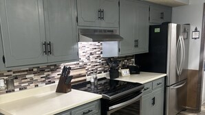 Una cuina moderna amb armaris grisos, un frigorífic d'acer inoxidable i una placa de cocció negra.