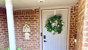 Fachada de maó amb una porta blanca, un felpó de benvinguda i un rètol que indica un Airbnb.